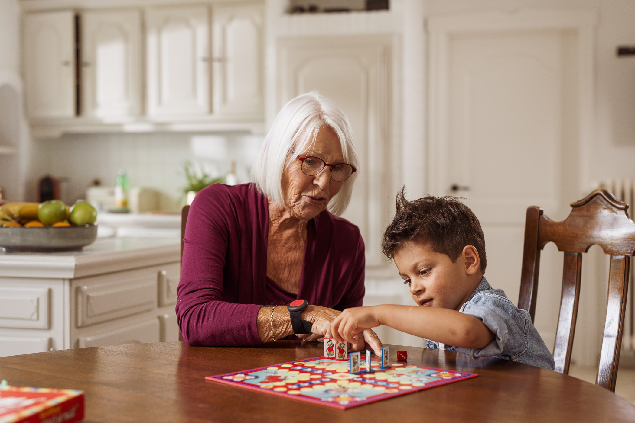 Dame met personenalarm speelt thuis bordspel met kleinkind.